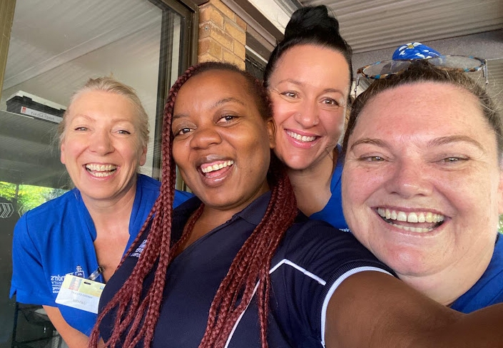 1.-Kundai-and-colleagues Woman smiling with colleagues.