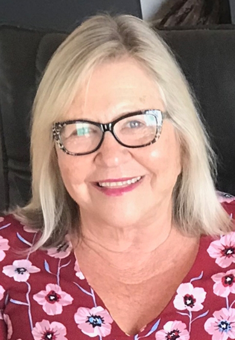 Person with blonde shoulder length hair and black rimmed glasses