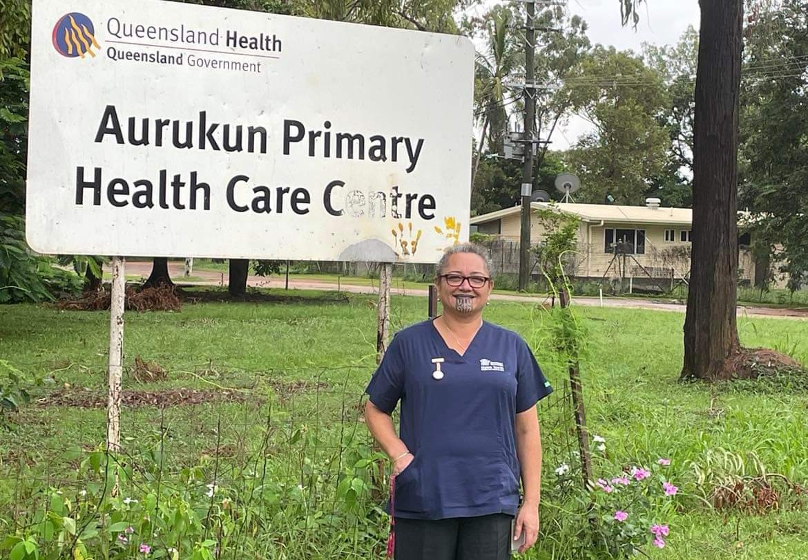 Leonie standing in front of Aurukun Primary Health Care Centre sign.